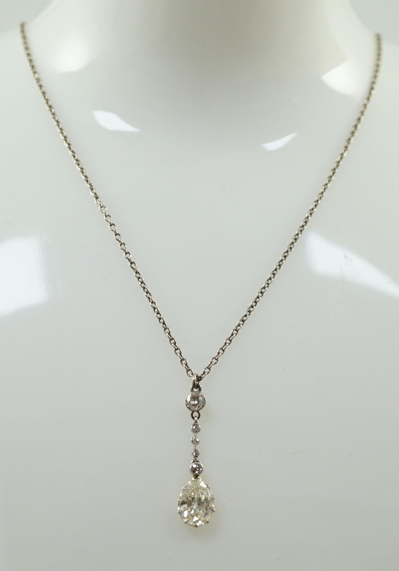 An early to mid 20th century white and yellow gold, six stone diamond set drop pendant, on a white gold chain, the clasp stamped 9k